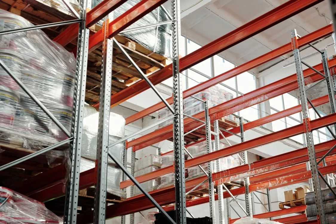 Warehouse racking stocked with wrapped pallets, part of the distribution operation behind the product data flow